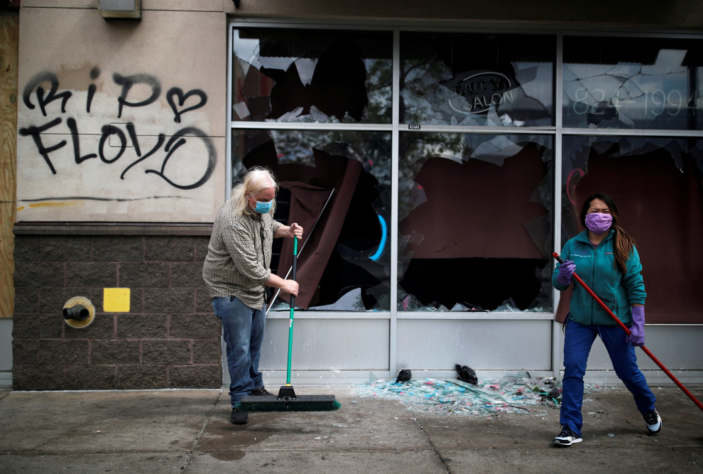 People clean up outside a local business in the area in the aftermath of a protest, in Minneapolis