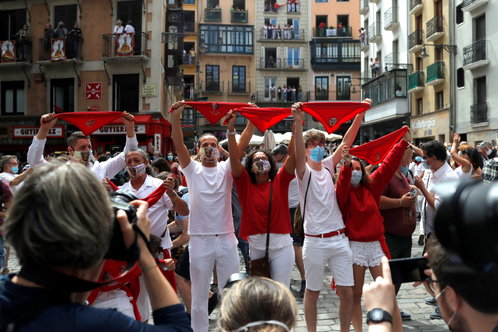 Revellers hold up traditional red scarves in front of the town hall where the firing of "chupinazo", which opens the San Fermin festival that was cancelled due to the coronavirus disease (COVID-19) outbreak, should have taken place, in Pamplona, Spain July 6, 2020. REUTERS/Jon Nazca [[[REUTERS VOCENTO]]] HEALTH-CORONAVIRUS/SPAIN-BULLS