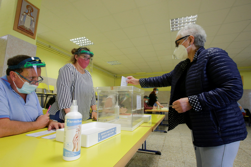 A woman, wearing a protective face mask, casts her vote at a polling station during Galicia's regional elections in Ribadeo