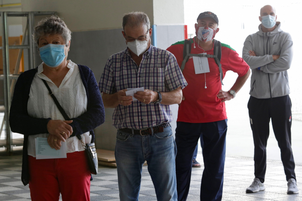 People, wearing protective face masks, queue while keeping social distancing as they wait to cast their votes during Galicia's regional elections in Ribadeo