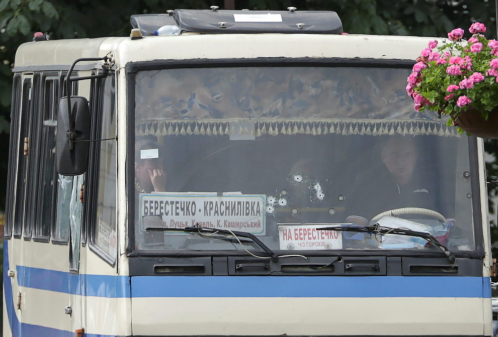 Ukrainian law enforcement officers lie on the ground behind a car near a passenger bus, which was seized by an unidentified person in the city of Lutsk, Ukraine July 21, 2020. REUTERS/Tetiana Hrishyna [[[REUTERS VOCENTO]]] UKRAINE-HOSTAGES/