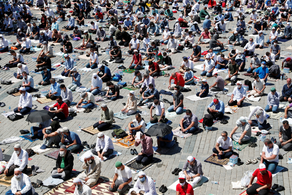 Turkey's President Tayyip Erdogan is seen on a screen reading the Koran as people wait for the beginning of Friday prayers outside Hagia Sophia Grand Mosque, for the first time after it was once again declared a mosque after 86 years, in Istanbul, Turkey, July 24, 2020. REUTERS/Umit Bektas [[[REUTERS VOCENTO]]] TURKEY-HAGIASOPHIA/