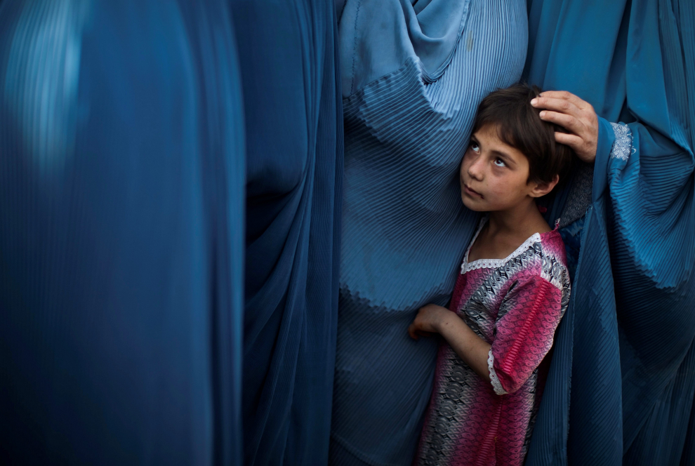 Año 2010. Una niña hace fila con su madre para recibir comida en Kabul.