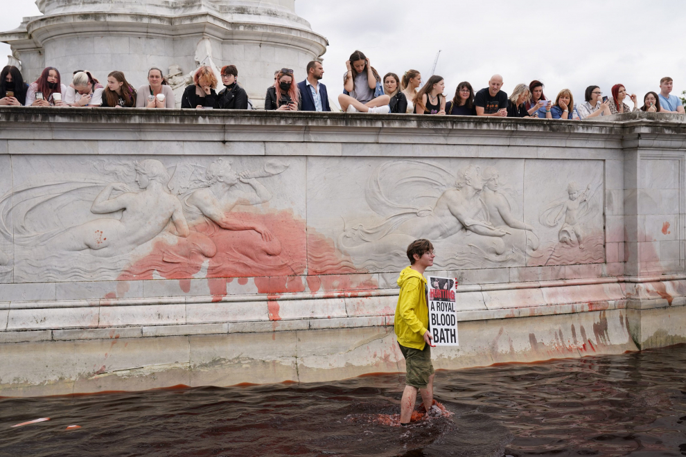 An Extinction Rebellion activist holds a placard and a flare in a fountain during a protest next to Buckingham Palace in London, Britain, August 26, 2021. REUTERS/John Sibley[[[REUTERS VOCENTO]]] CLIMATE-CHANGE/BRITAIN-PROTESTS