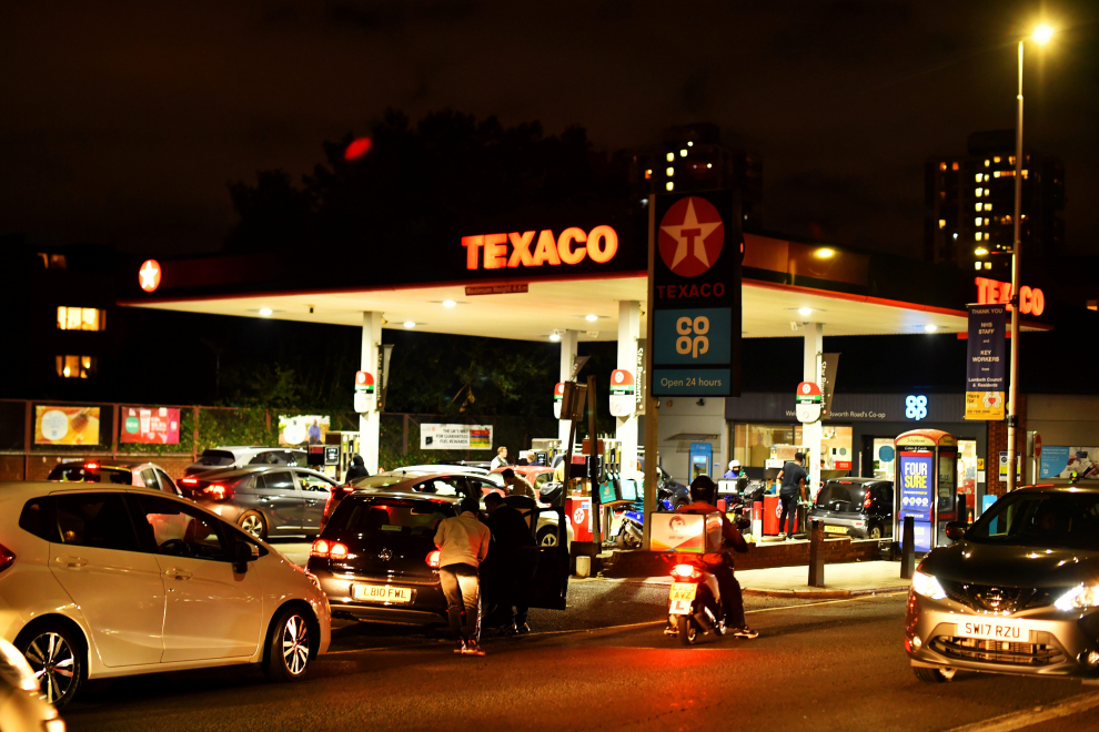 People push as a car, which has run out of petrol, the final few meters on to the forecourt as vehicles queue to refill at a Texaco fuel station in south London, Britain, September 26, 2021. Picture taken September 26, 2021.  REUTERS/Dylan Martinez[[[REUTERS VOCENTO]]] POWER-PRICES/BRITAIN