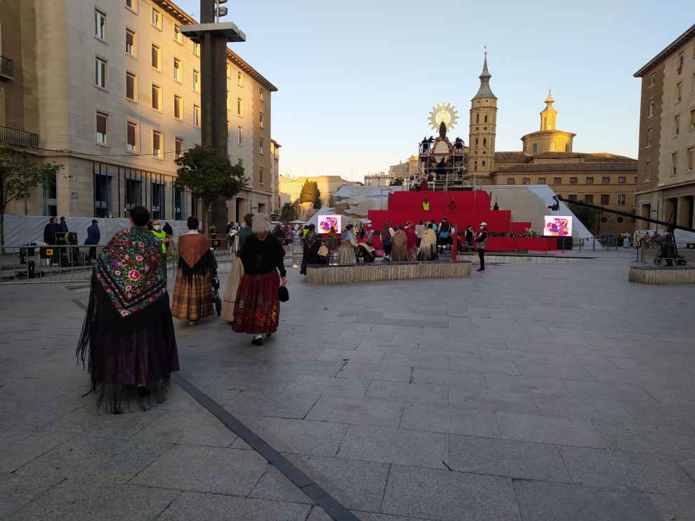 El manto de la Virgen se comienza a cubrir con flores y los oferentes van llenando de color una plaza del Pilar que permanece cubierta para el público.