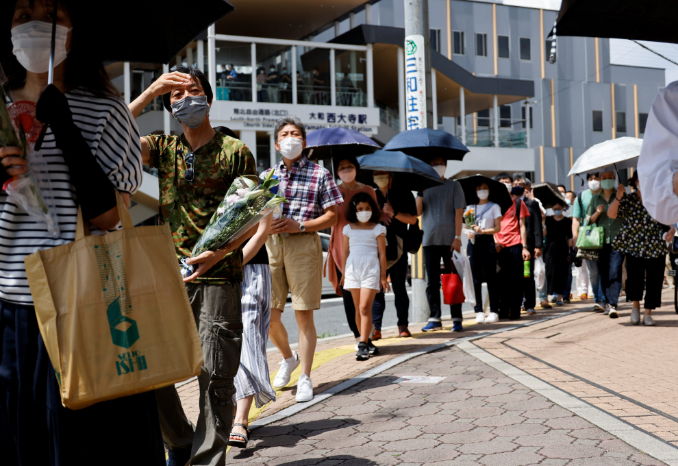 A man offers flowers at the site where late former Japanese Prime Minister Shinzo Abe was shot while campaigning for a parliamentary election, near Yamato-Saidaiji station in Nara, Japan, July 9, 2022. REUTERS/Issei Kato JAPAN-ABE/
