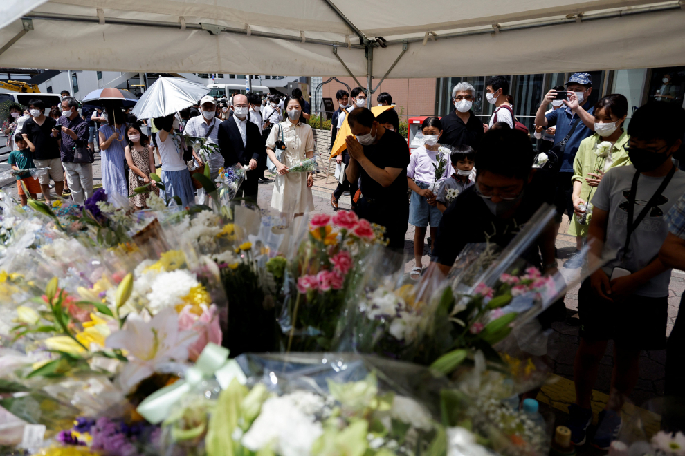 People queue up to offer flowers and pray at the site where late former Japanese Prime Minister Shinzo Abe was shot while campaigning for a parliamentary election, near Yamato-Saidaiji station in Nara, Japan, July 9, 2022.  REUTERS/Issei Kato JAPAN-ABE/