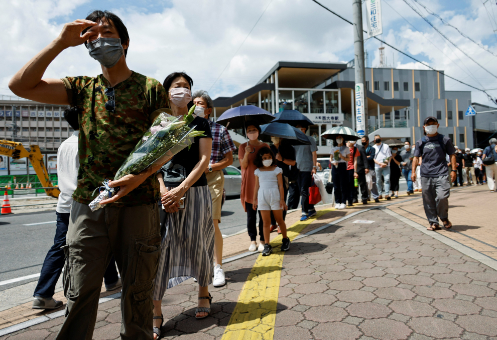 People queue up to offer flowers and pray at the site where late former Japanese Prime Minister Shinzo Abe was shot while campaigning for a parliamentary election, near Yamato-Saidaiji station in Nara, Japan, July 9, 2022.  REUTERS/Issei Kato JAPAN-ABE/