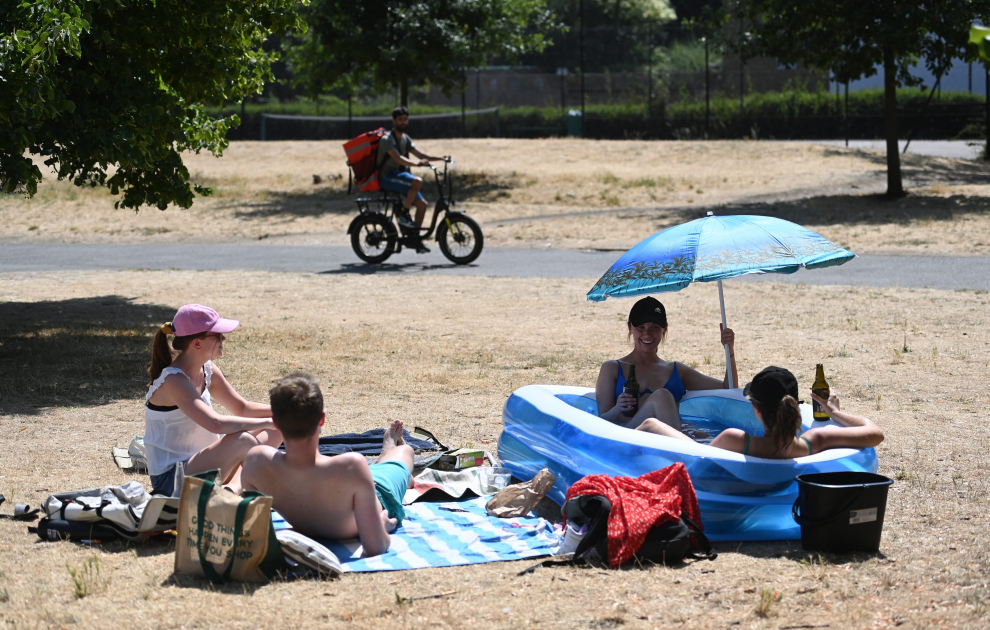London (United Kingdom), 18/07/2022.- Friends sit in a kiddies paddling pool after a council parks vehicle filled their pool with water at a park in central London, Britain, 18 July 2022. The Met Office has issued a red extreme heat warning as the UK could have its hottest day on record this week, with temperatures forecast to hit up to 41 Celsius. (Reino Unido, Londres) EFE/EPA/ANDY RAIN
 BRITAIN WEATHER