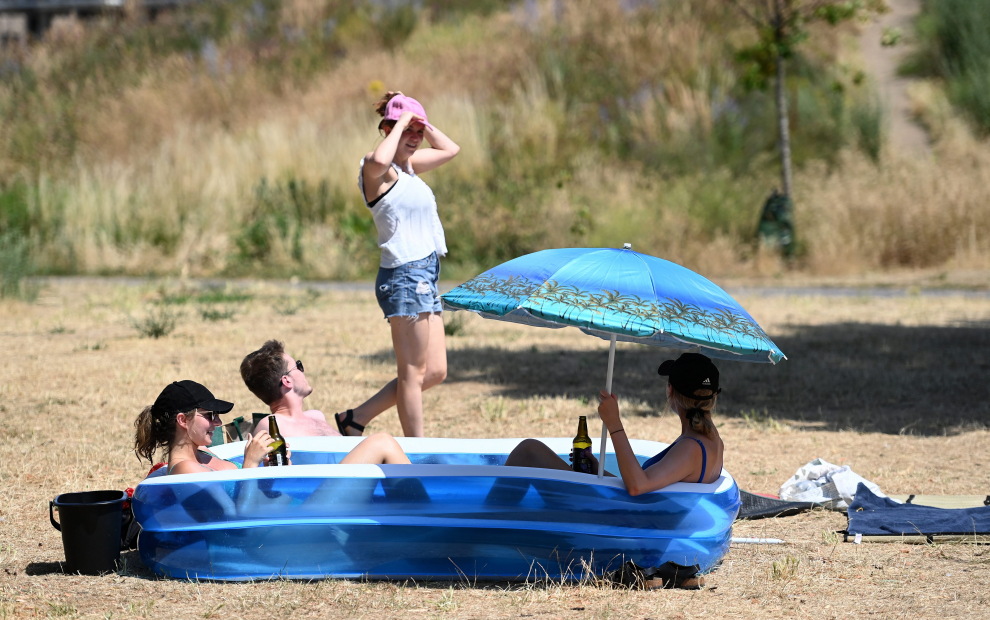 London (United Kingdom), 18/07/2022.- Friends sit in a kiddies paddling pool after a council parks vehicle filled their pool with water at a park in central London, Britain, 18 July 2022. The Met Office has issued a red extreme heat warning as the UK could have its hottest day on record this week, with temperatures forecast to hit up to 41 Celsius. (Reino Unido, Londres) EFE/EPA/ANDY RAIN
 BRITAIN WEATHER