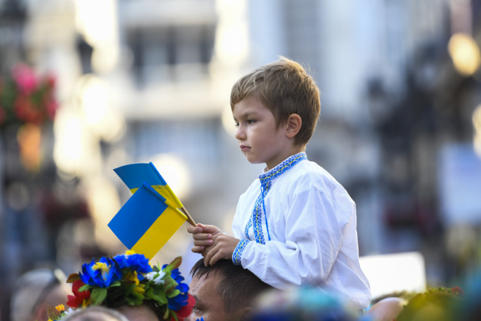 Un niño con camisa blanca y banderas de Ucrania.