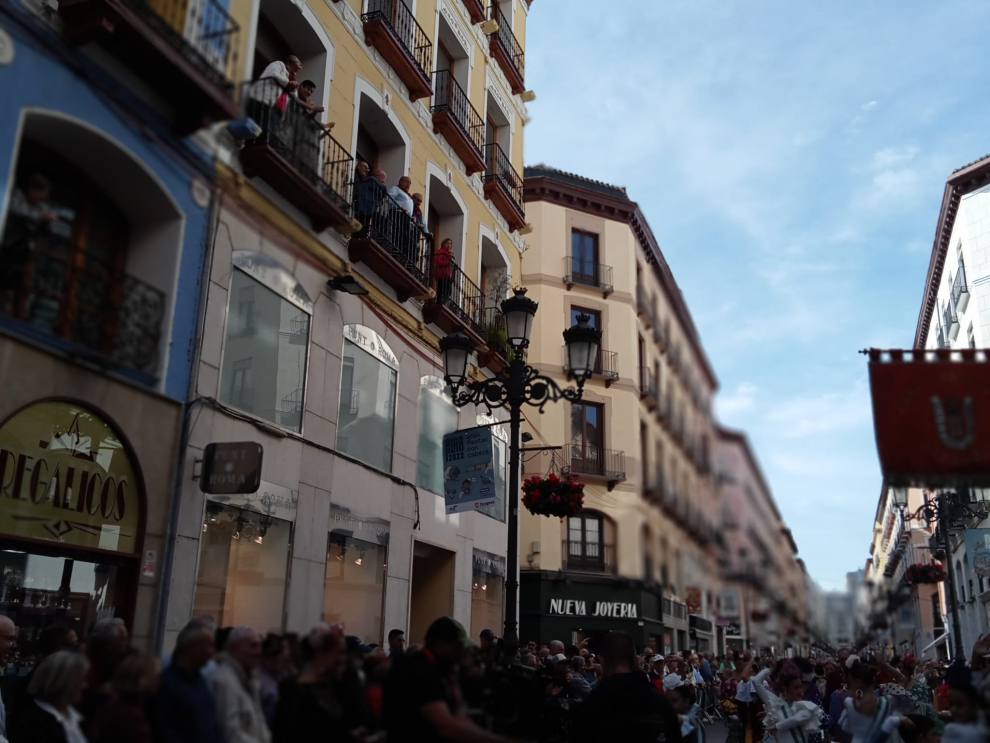 Un señor canta sevillanas desde un balcón al paso del numeroso grupo de la Casa de Andalucía