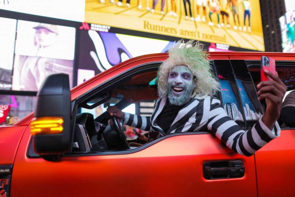 People in costume drive a convertible car in Times Square on Halloween in Manhattan, New York City, U.S., October 31, 2022.  REUTERS/Andrew Kelly HALLOWEEN-DAY/NEW YORK