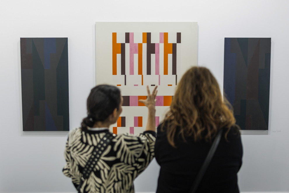 Dos mujeres contemplan obras pertenecientes a la exposición de Henrique Faria.