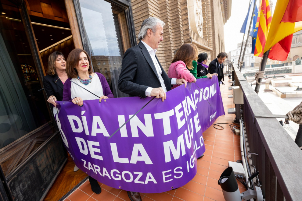 El alcalde de Zaragoza, Jorge Azcón, portando la pancarta feminista que cuelga en el balcón del Consistorio
