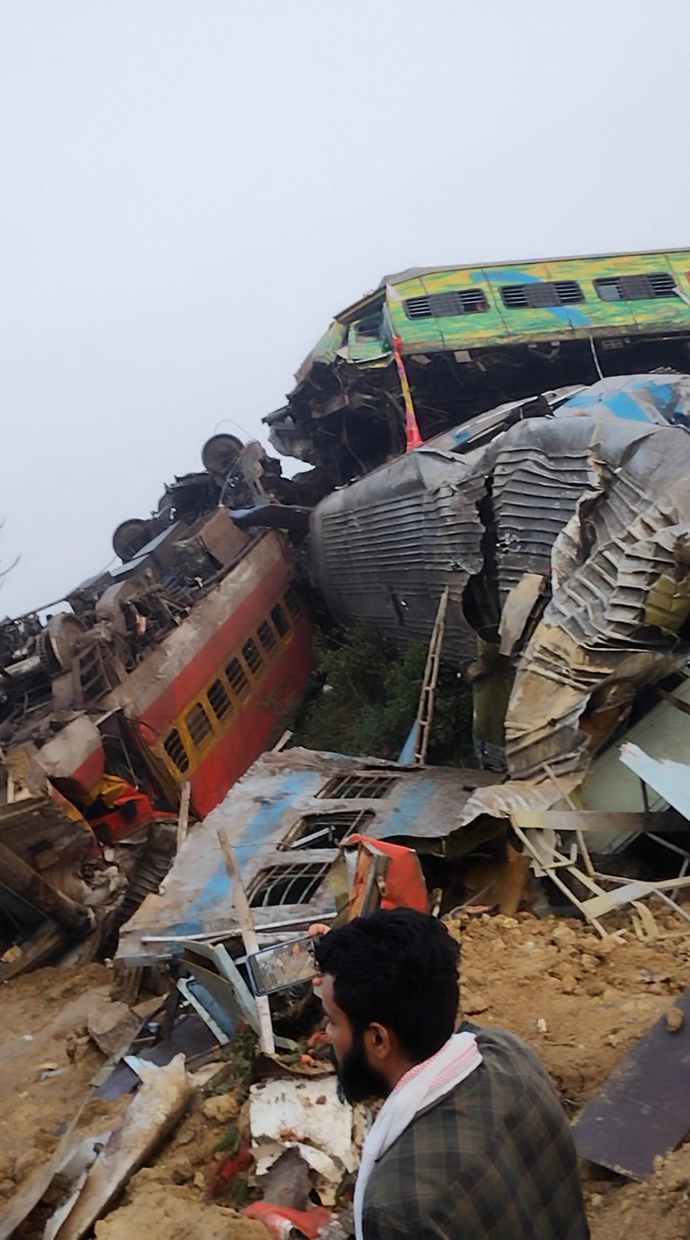 People stand next to a damaged coach, after trains collided in Balasore, India June 3, 2023, in this screen grab obtained from a social media video. Nantu Samui/via REUTERS  THIS IMAGE HAS BEEN SUPPLIED BY A THIRD PARTY. MANDATORY CREDIT. NO RESALES. NO ARCHIVES. INDIA-CRASH/RAIL