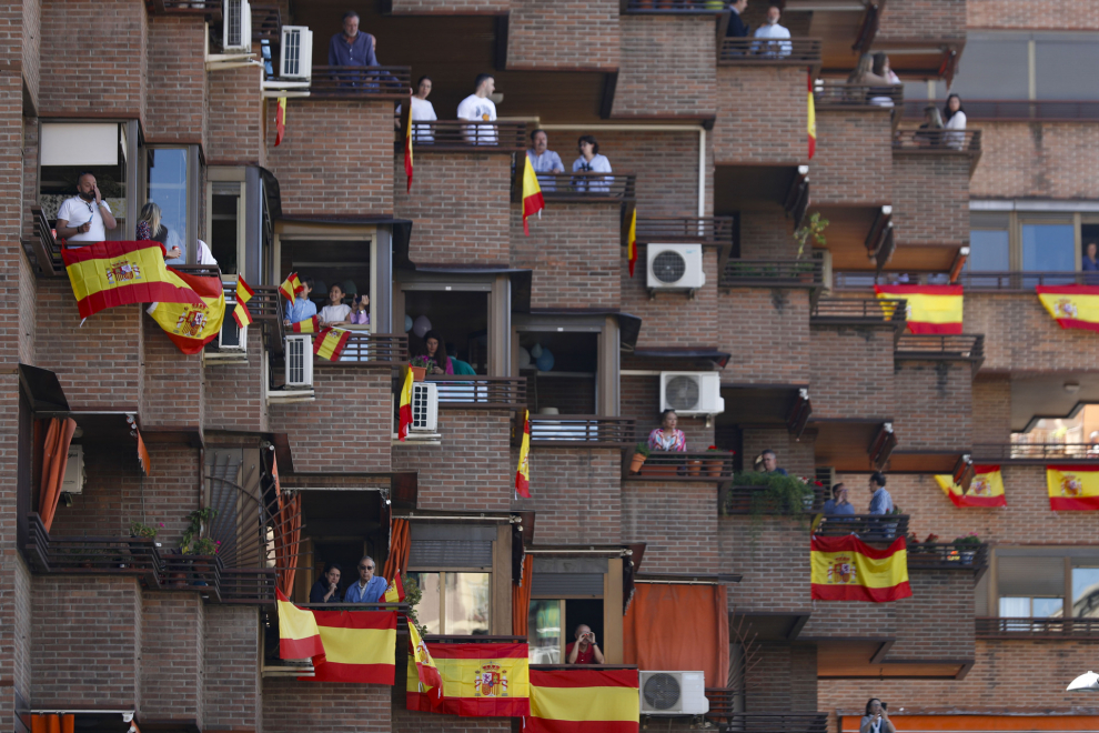 Vecinos de Granada esperan desde sus balcones, engalanados con banderas de España, a que comience el desfile del Día de las Fuerzas Armadas este sábado en Granada.