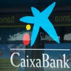 FILE PHOTO: Logos of Caixabank and Bankia are seen in bank offices near Barcelona