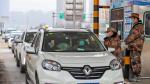 Un militar comprueba la temperatura de dos personas en un coche en Wuhan.