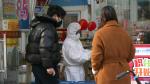 El dependiente de una farmacia de Wuhan a los clientes con un traje de protección por el coronavirus