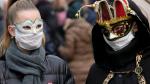 Dos personas pasean por Venecia con máscaras de carnaval y mascarillas protectoras.