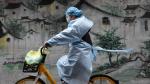 Una mujer en bici se protege del coronavirus en Wuhan, epicentro de la epidemia en China
