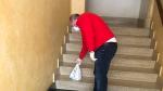 Un voluntario deposita una bolsa de medicamentos en las escaleras de acceso a una vivienda