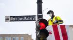 Un tabajador municipal coloca la placa con el nombre 'Black Lives Matter' en una calle de Washington.