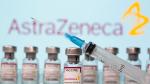 Vials labelled "AstraZeneca COVID-19 Coronavirus Vaccine" and a syringe are seen in front of a displayed AstraZeneca logo
