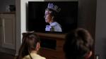 Unos niños ven el anuncio de la muerte de Isabel II en televisión.