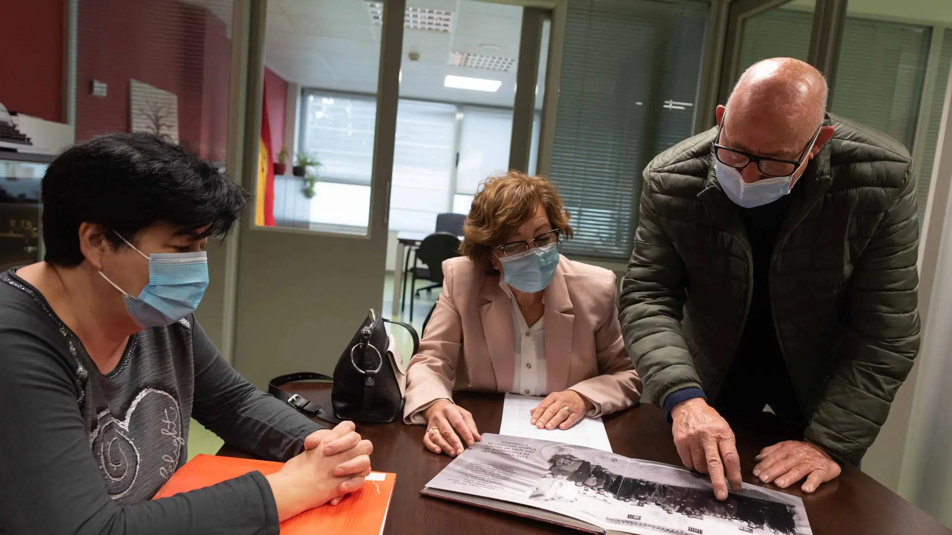 Manuel Morón les muestra a Nieves Borraz y Mercedes Abós imágenes de la riada de hace 60 años.