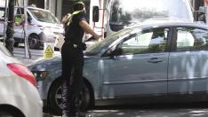 Un policía local de Zaragoza pone una multa a un coche mal aparcado.