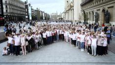 Decenas de personas vestidas con camisetas rosas han formado un lazo humano en la plaza del Pilar de Zaragoza este sábado al mediodía.