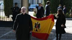 El sacerdote Ramón Tejero, que ha oficiado la misa de la reinhumación de Francisco Franco, a su salida del cementerio de Mingorrubio junto a dos familiares del dictador que portan una bandera española con el escudo franquista.