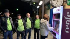 Una viajera saca el billete en la máquina en Monzón, en presencia de miembros del colectivo que se ha movilizado.