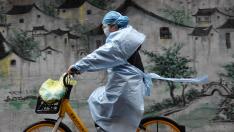 Una mujer en bici se protege del coronavirus en Wuhan, epicentro de la epidemia en China.