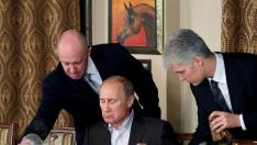 FILE PHOTO: FILE PHOTO: Evgeny Prigozhin assists Russian Prime Minister Vladimir Putin during a dinner with foreign scholars and journalists at the restaurant Cheval Blanc on the premises of an equestrian complex outside Moscow