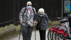 Dos mujeres con mascarillas caminan al lado de un hospital de Londres.