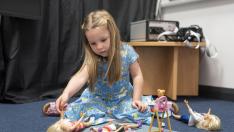 Una niña juega con varias muñecas.