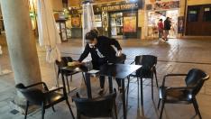 Una trabajadora recoge mesas de un bar de la calle de San Juan de Teruel