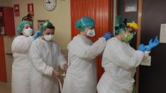 Las auxiliares María José, Silvia y Lara y la enfermera Raquel, colocándose los equipos de protección para la jornada.