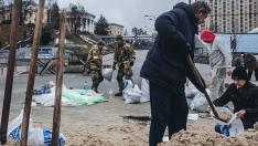 Soldados y voluntarios cargan sacos de arena para construir barricadas en la plaza Maidan de Kiev.