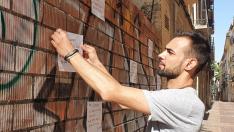 Caio Machado, colocando un cartel en la pared de la tapia ubicada en el solar del número 11 de la calle Casta Álvarez de Zaragoza