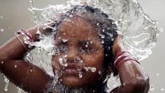 Una niña se baña bajo un chorro de agua en Ahmedabad, en la India.