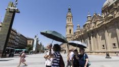 Los turistas buscan protegerse del sol en la plaza del Pilar.