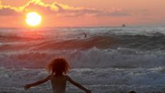 Unas niñas disfrutan del oleaje en la playa de la Zurriola, de San Sebastián, al atardecer