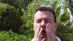 Un hombre estornudando a causa de la alergia al polen.