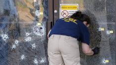 Una agente del FBI inspecciona un cristal lleno de disparos