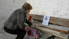 Una vecina de Peñalba pone una vela en el banco roto tras el suceso donde estaba sentada  la víctima cuando el turismo la arrolló y en el que ayer se dejaron flores y mensajes de condolencia.